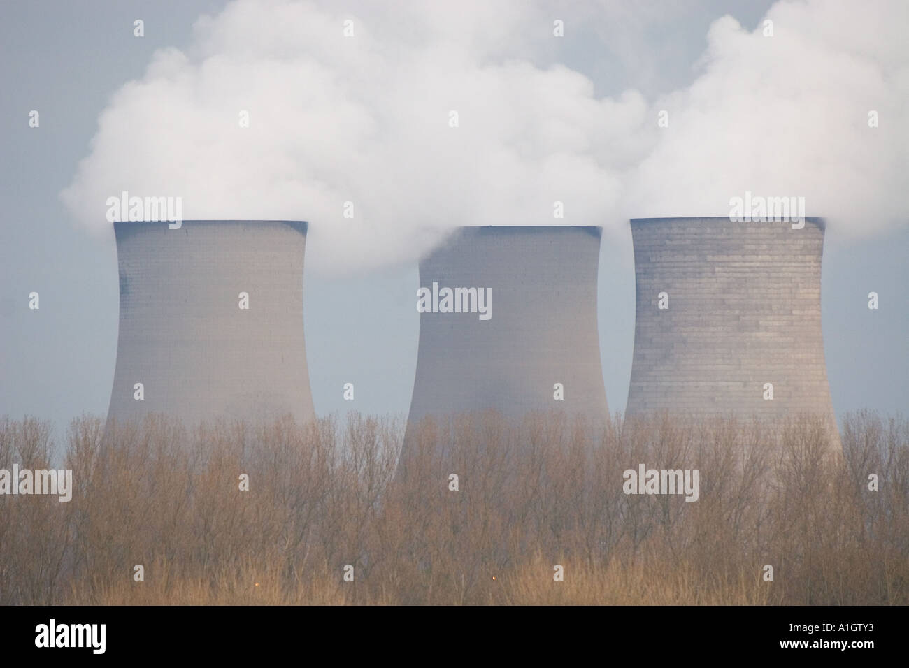 Three power station cooling towers pump out water vapour into the
