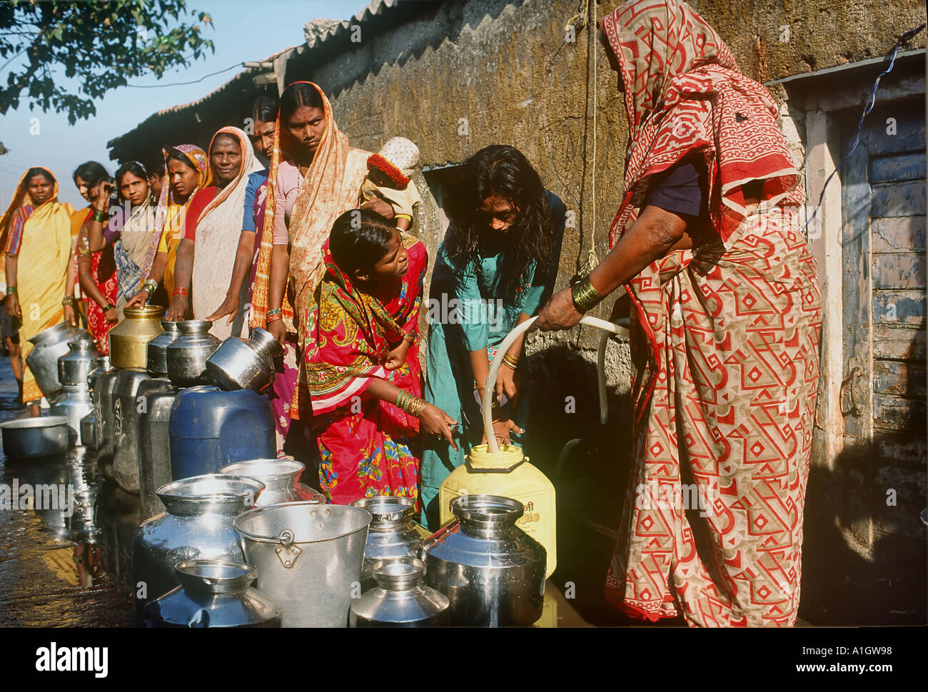 Women in line in slum with their vessels to collect their daily requirement of water from a community tap Bombay Mumbai Maharashtra India Asia Stock Photo