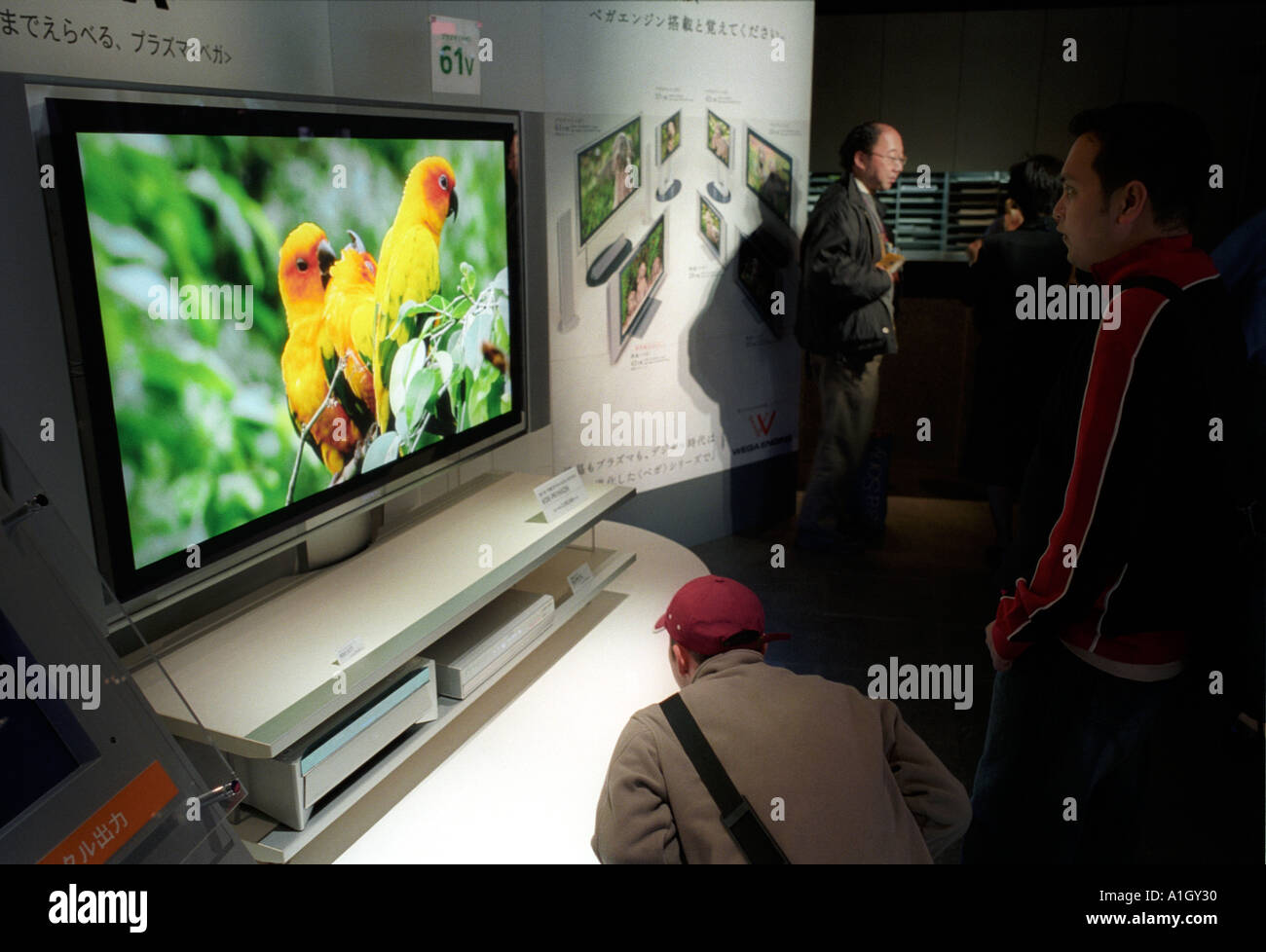 Shoppers check a new wide screen television in Tokyo electronic appliances showroom Stock Photo