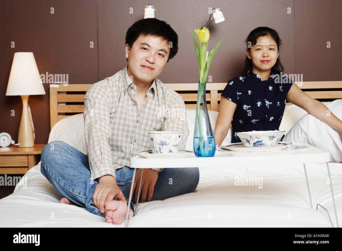 Portrait of a young man and a mid adult woman sitting on the bed Stock ...
