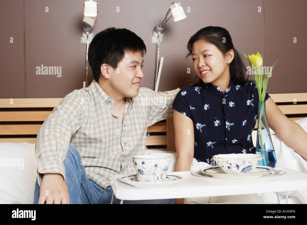 Close-up of a young man and a mid adult woman sitting on the bed Stock ...