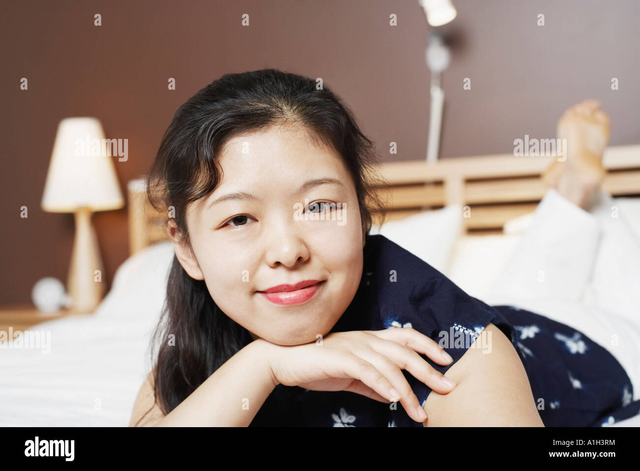 Portrait of a young woman lying on the bed smiling Stock Photo - Alamy