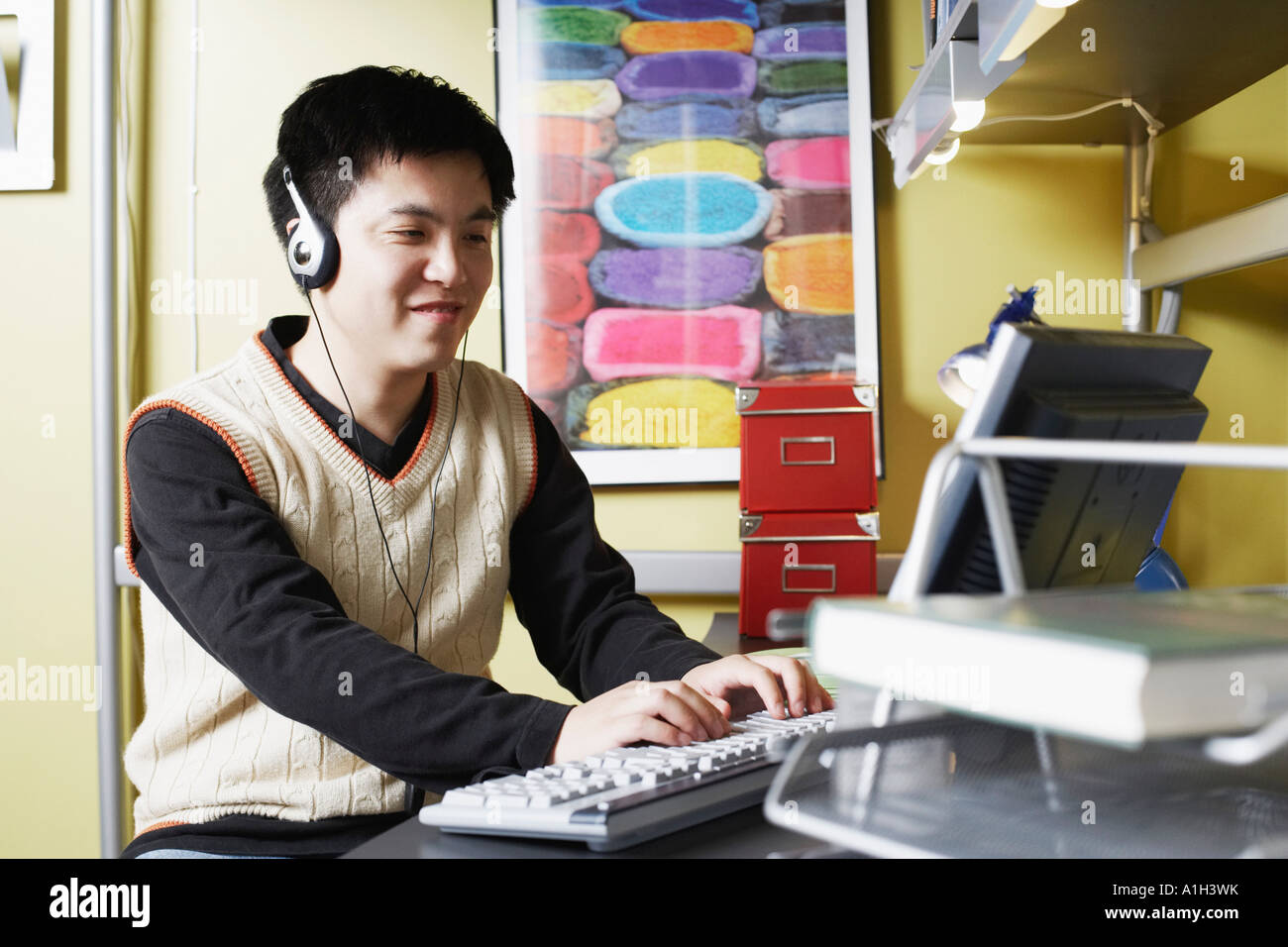 Close-up of a young man using a computer listening to music on headphones Stock Photo