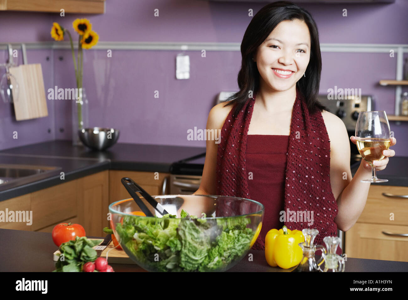 Portrait of a young woman holding a wineglass smiling in the kitchen Stock Photo