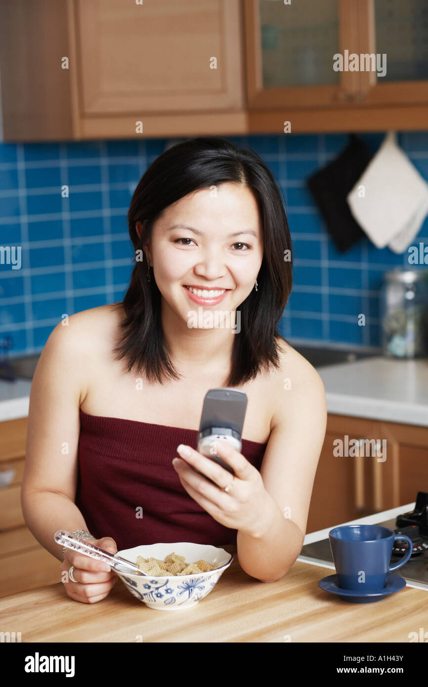 Portrait of a young woman holding a mobile phone smiling Stock Photo
