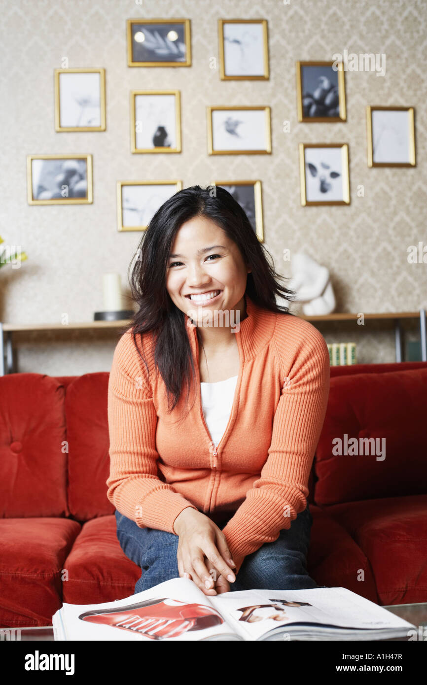 Portrait of a young woman sitting on a couch smiling Stock Photo - Alamy