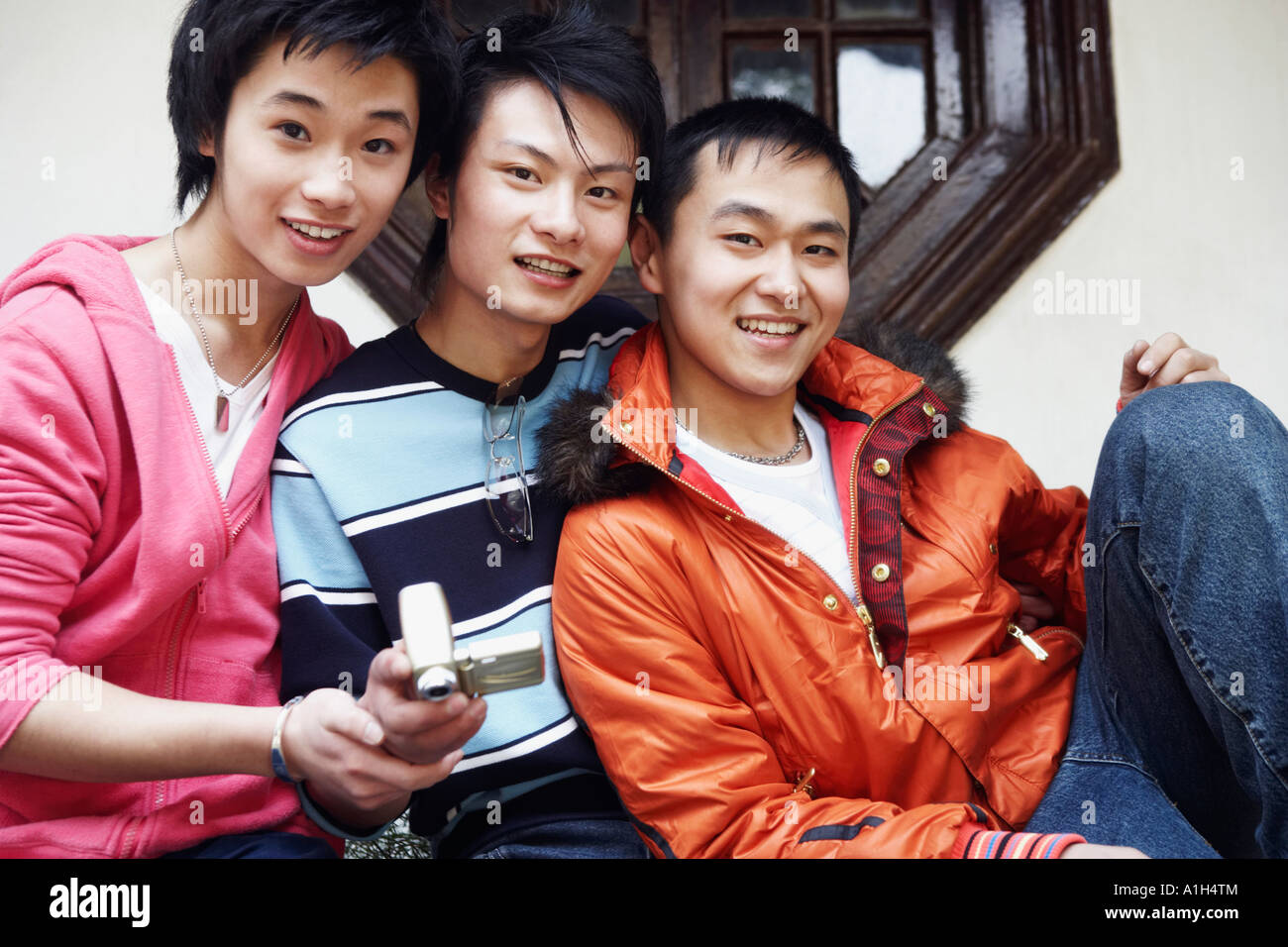 Portrait of a teenage boy smiling with two young men Stock Photo - Alamy