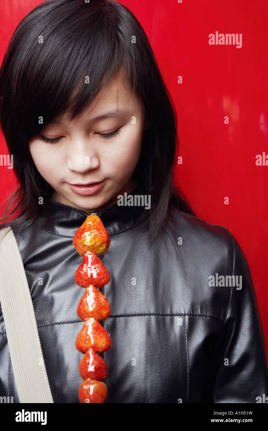 Close-up of a young woman holding avocado's on a stick Stock Photo