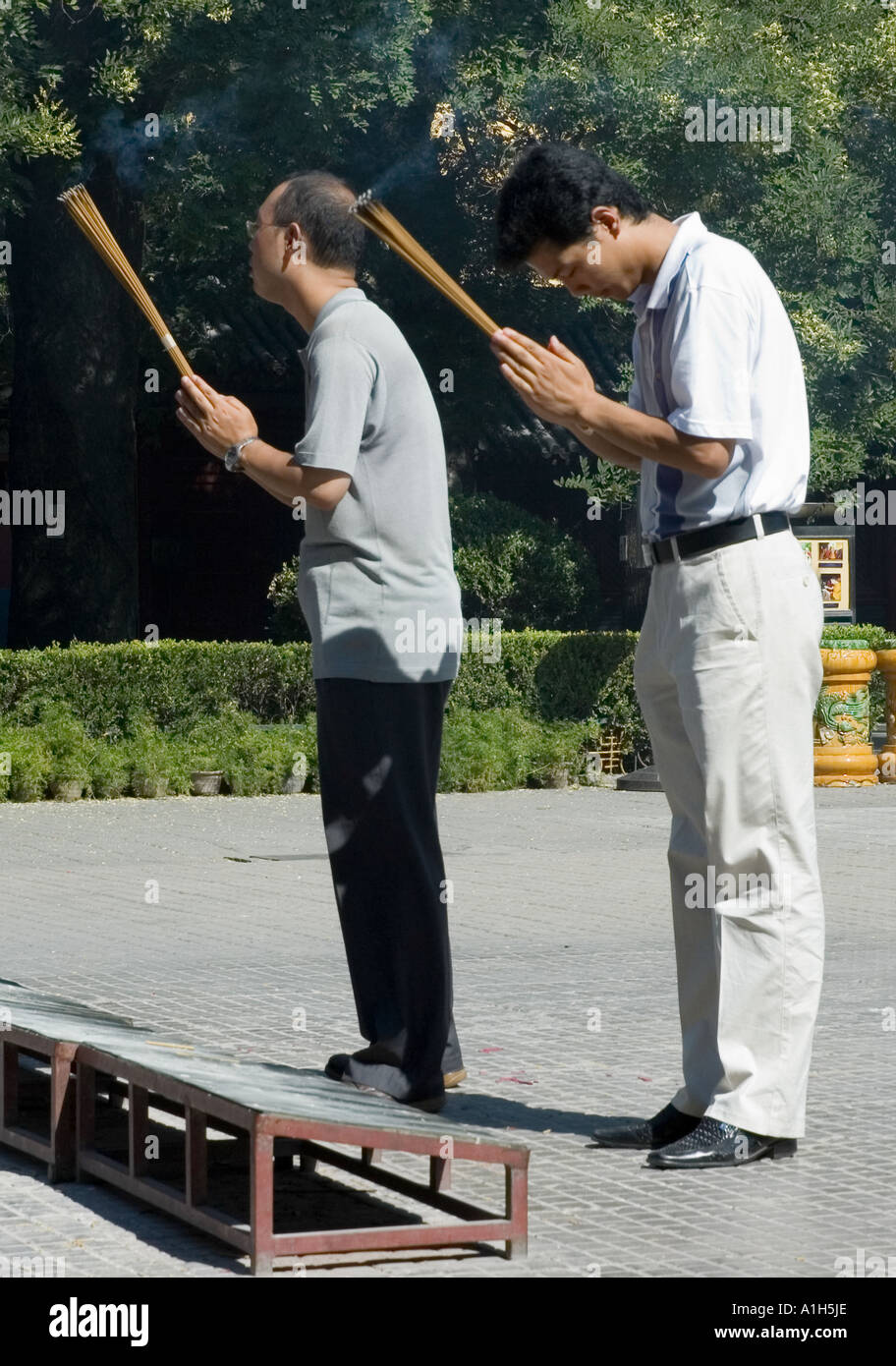 Two buddhist men praying holding incense sticks Stock Photo - Alamy