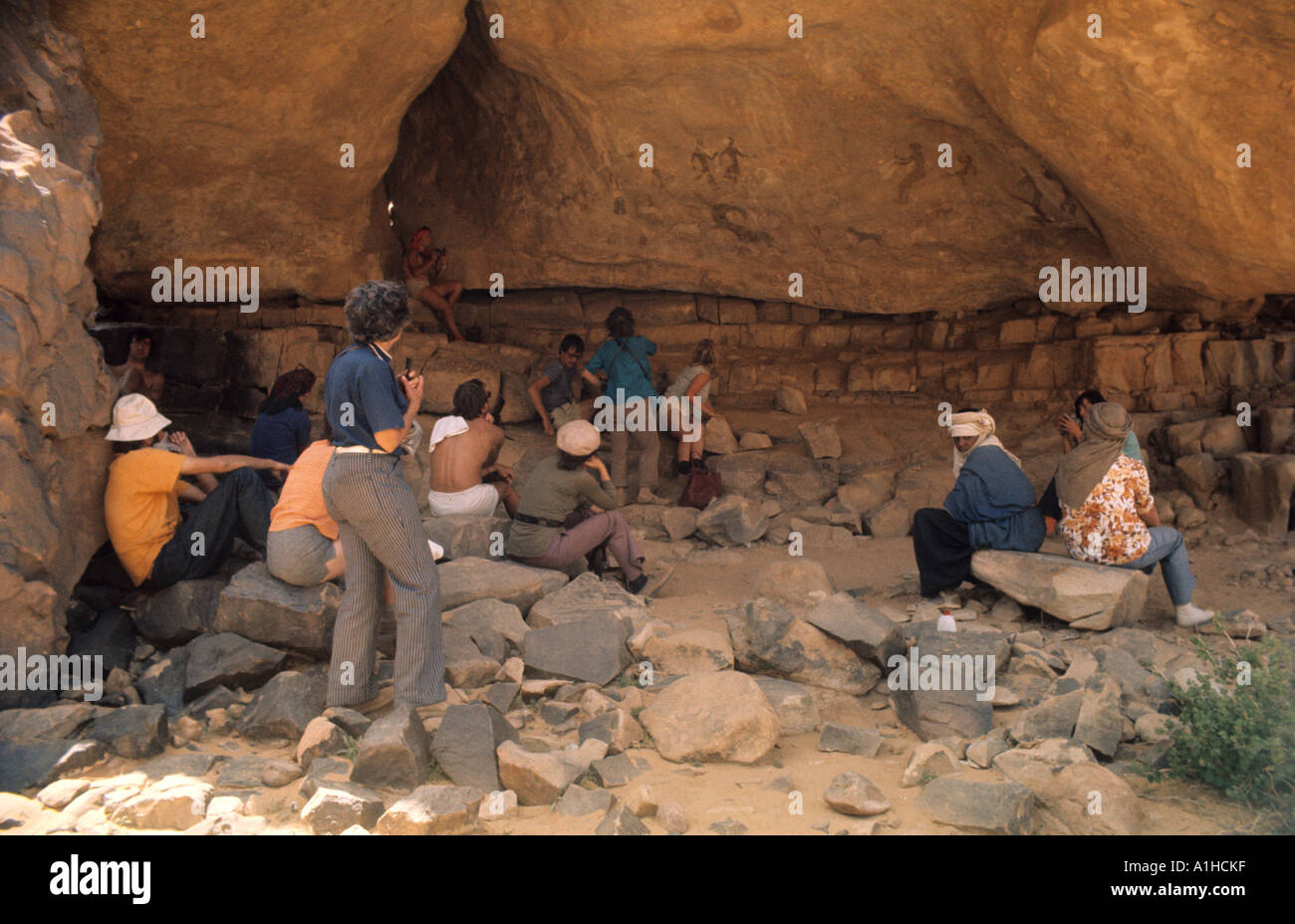 Group sitting in shade to admire rock frescoes at Tanzoumaitak on the Tassili n Ajjer plateau above Djanet Sahara Algeria Stock Photo