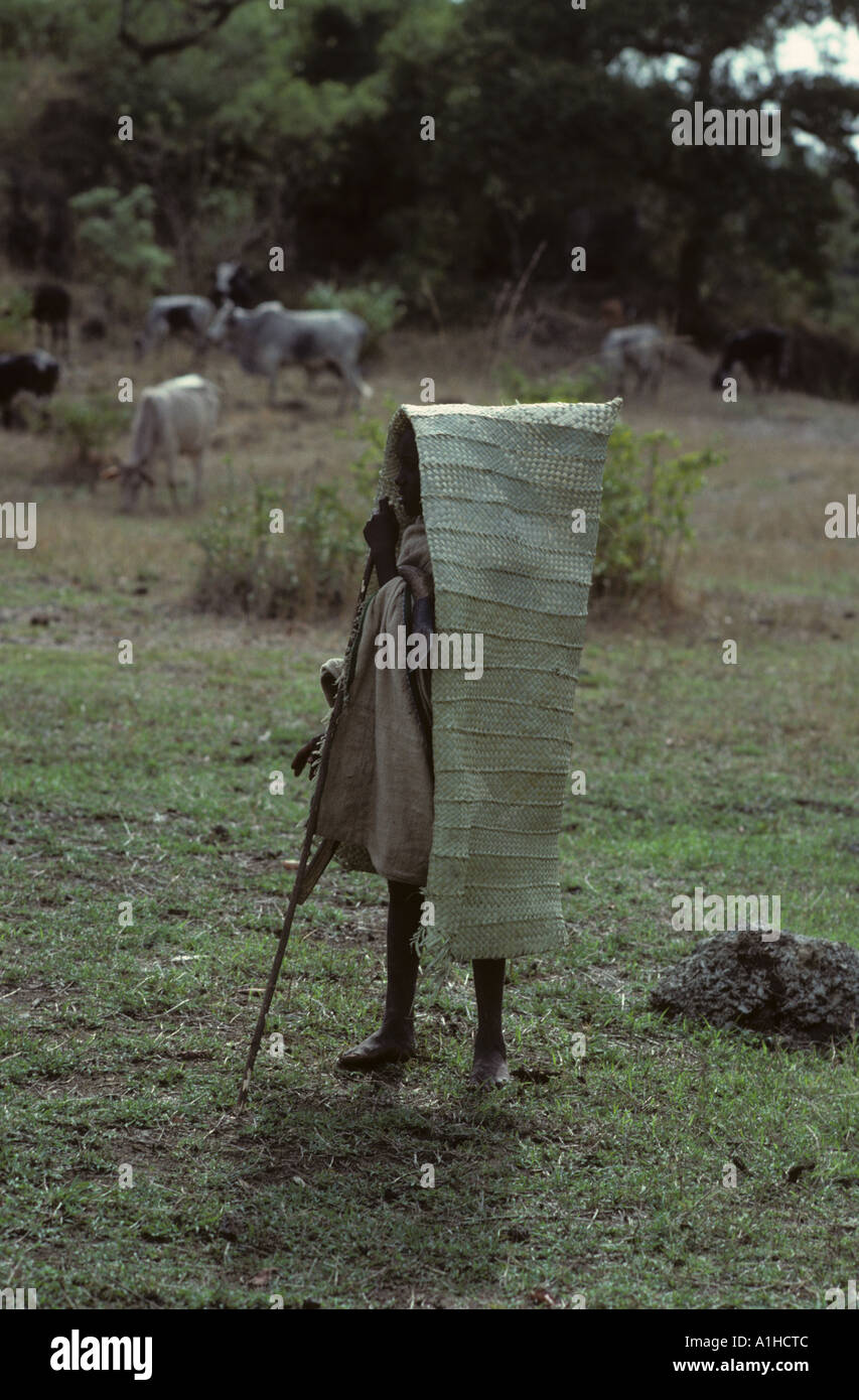 Boy cattle herder wearing rain cover woven from reeds near Tissisat Waterfalls Blue Nile Ethiopia Africa Stock Photo