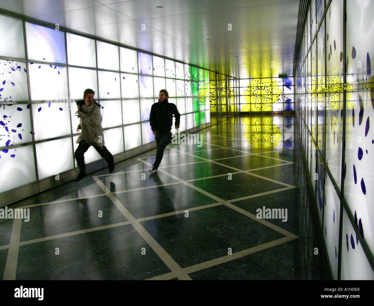 Couple running through lit tunnel, Canary Wharf, London Stock Photo