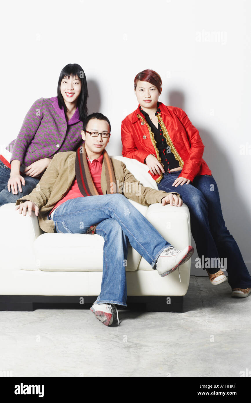 Portrait of a young man sitting with two young women Stock Photo - Alamy