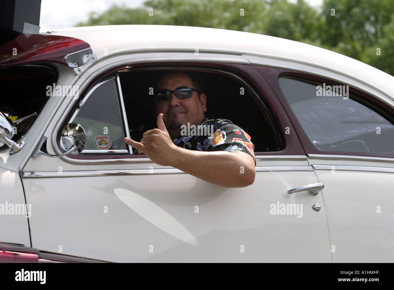 Man driving looking out of a classic old car window giving the thumbs up sign Stock Photo