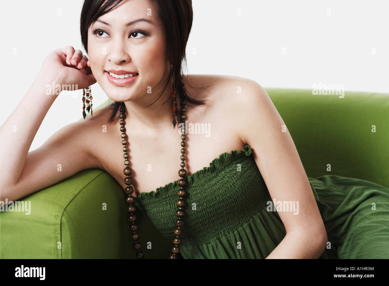 Close-up of a young woman sitting on a couch smiling Stock Photo - Alamy