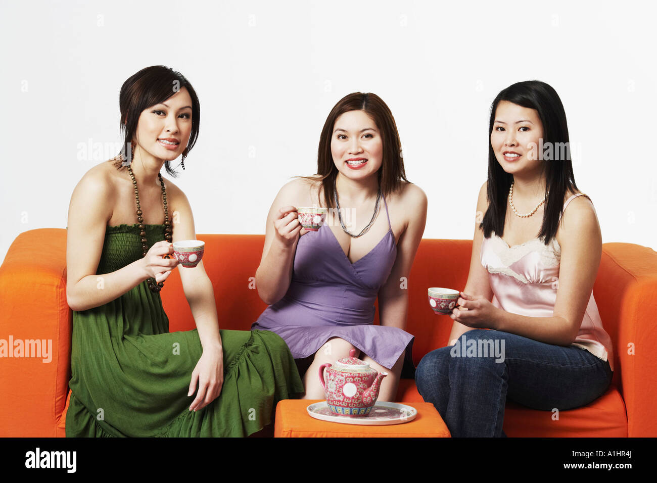 Portrait of three young women sitting on a couch with tea cups Stock ...