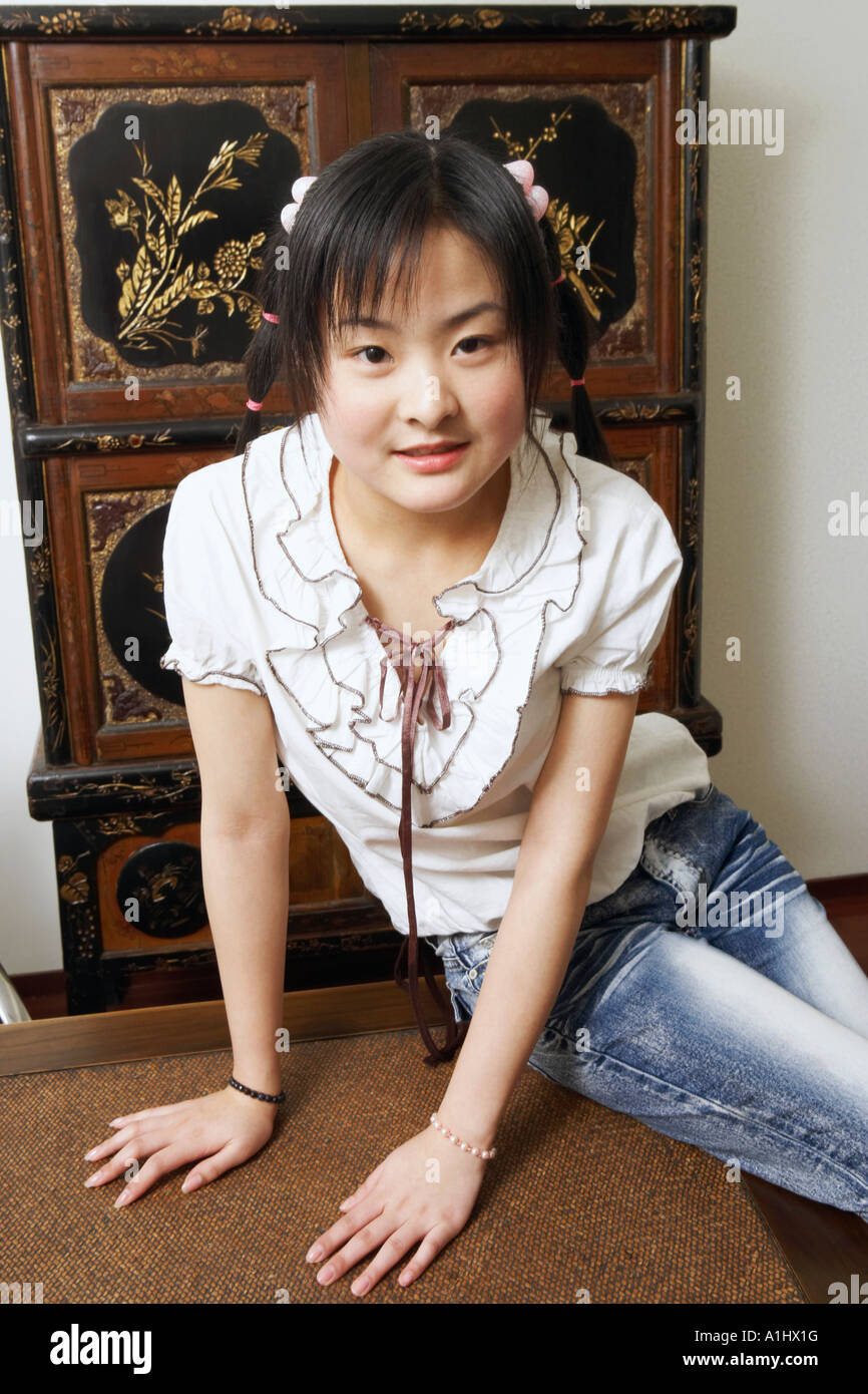 Portrait of a young woman sitting on the table Stock Photo - Alamy