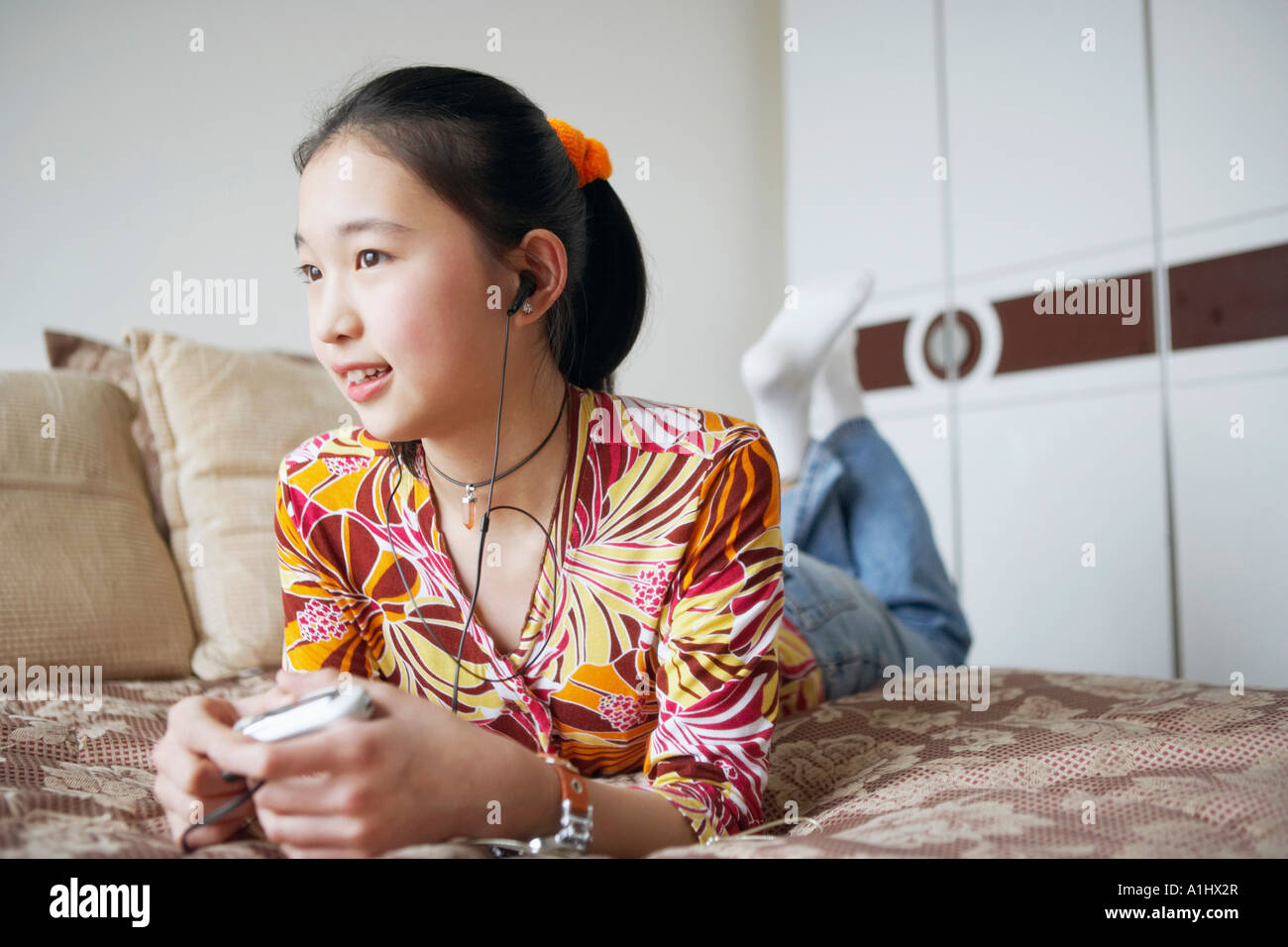 Close-up of a young woman lying on the bed listening to music Stock ...