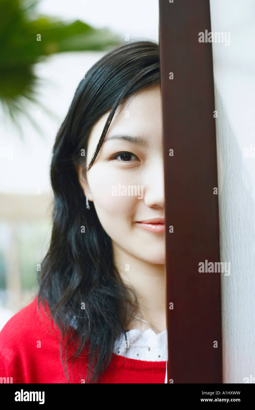 Portrait of a young woman standing behind a door Stock Photo - Alamy