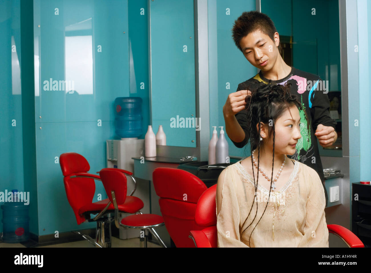 Closeup of a hairdresser adjusting a young woman's hair Stock Photo