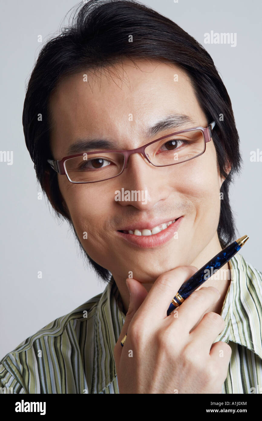 Portrait of a mid adult man holding a pen with his hand on his chin ...
