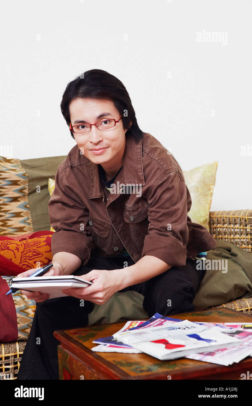 Portrait of a mid adult man sitting on a couch and holding a diary ...