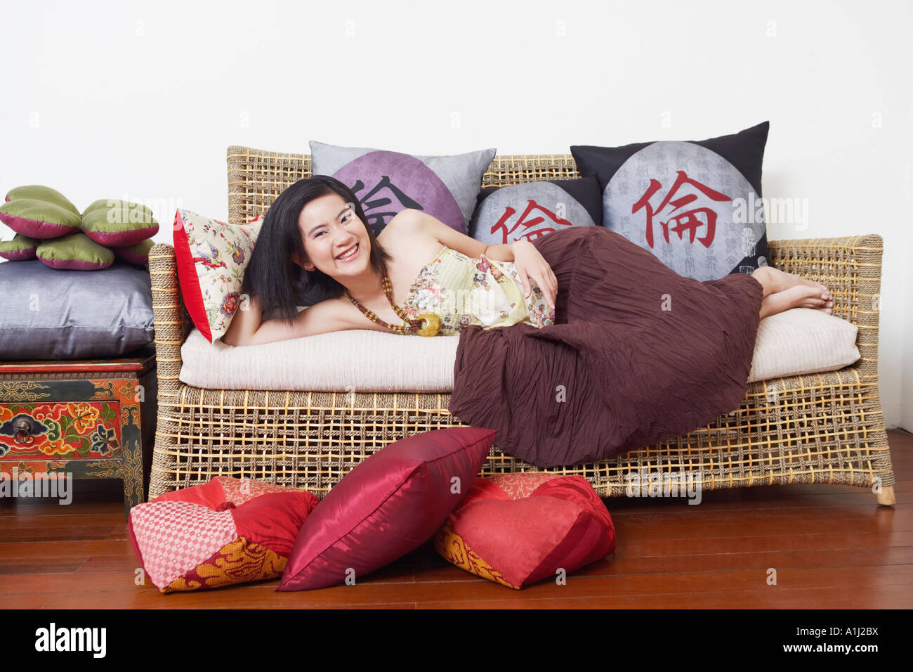 Portrait of a young woman lying on a couch and smiling Stock Photo - Alamy