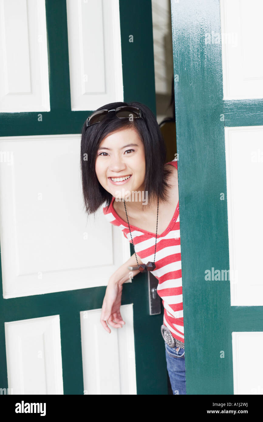 Portrait of a young woman smiling and standing at the door Stock Photo ...