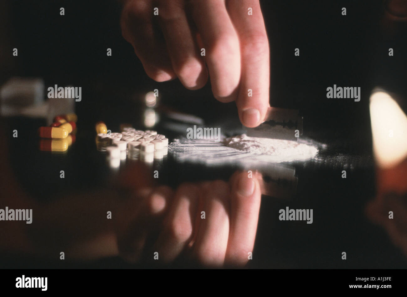 Close up hand cutting cocaine with razor Stock Photo