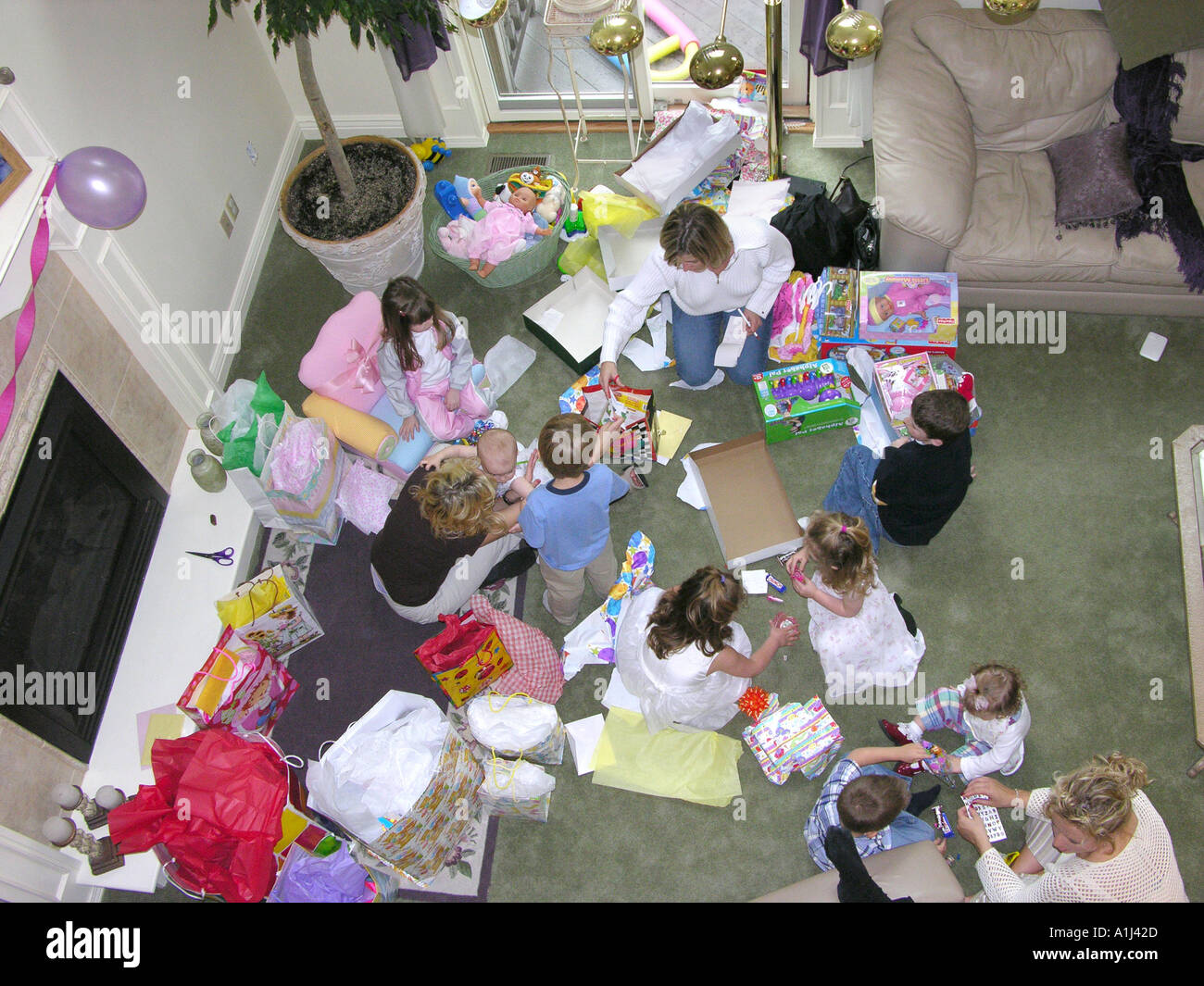 Family gathers to celebrate a family member baby s first birthday with presents and a party Stock Photo