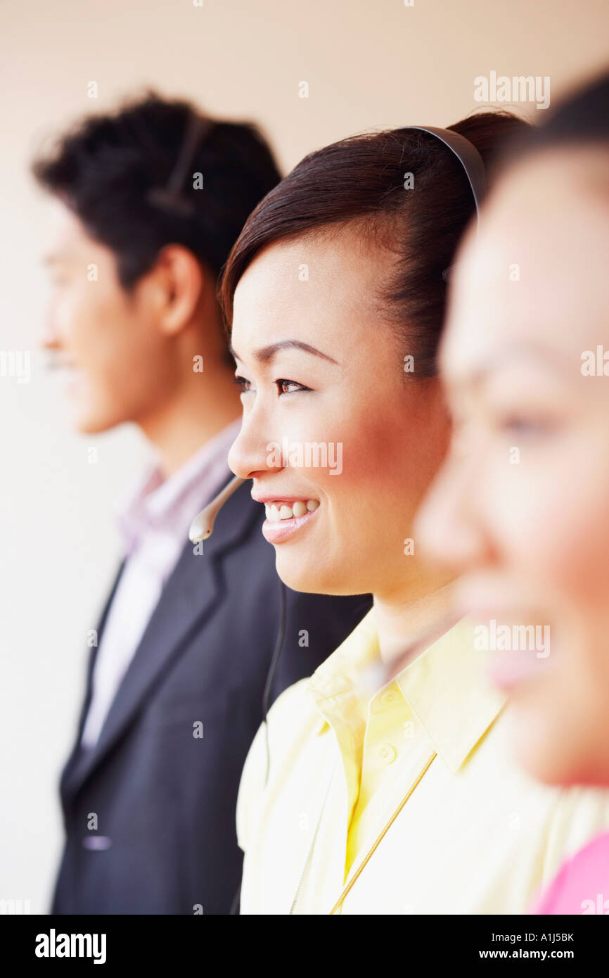Side profile of a female customer service representative smiling with two colleagues Stock Photo