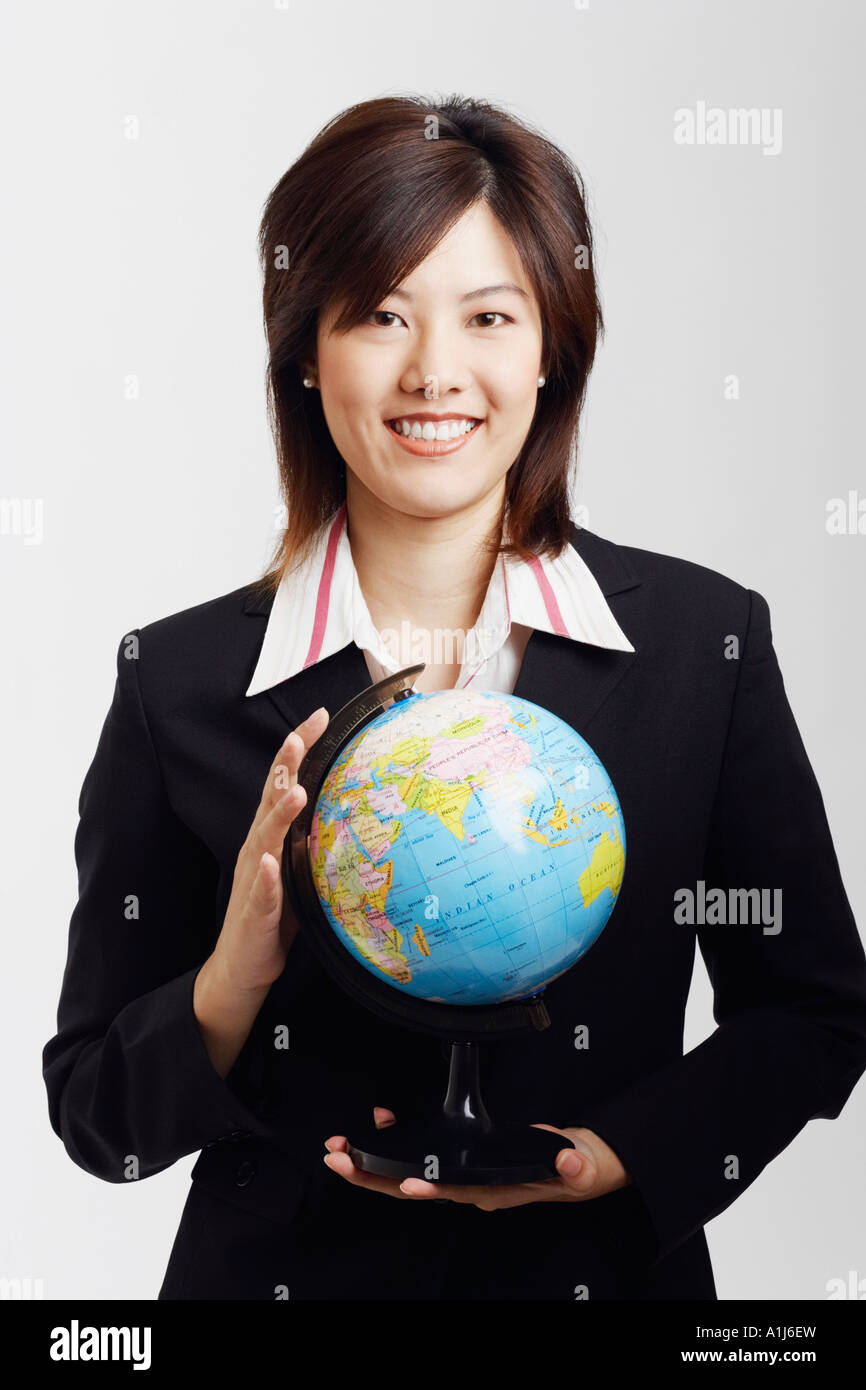 Portrait of a businesswoman holding a globe and smiling Stock Photo