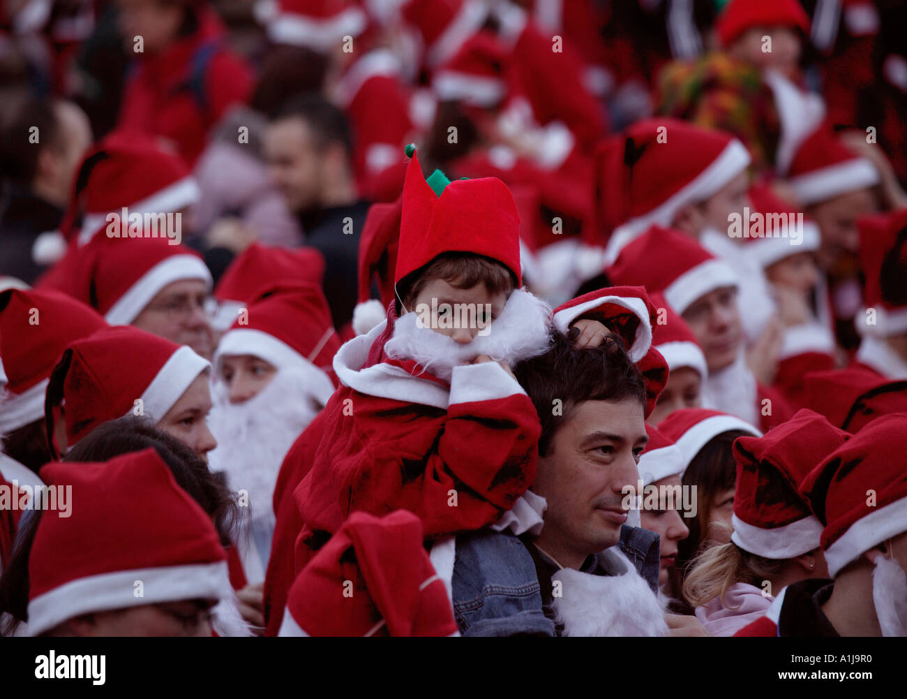 Young boy surrounded by people dressed as Santa preparing for Santa Run, Edinburgh, Scotland Stock Photo