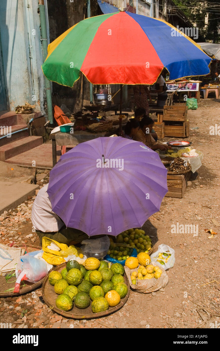 Colourful umbrellas keep the intense sunlight and heat off the street vendors and their produce - fruit that they are selling. Southeast Asia Stock Photo