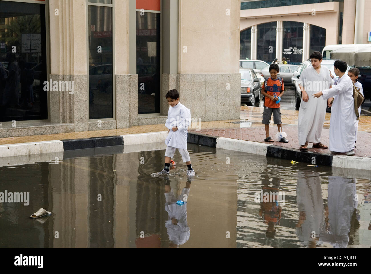 Abu Dhabi United Arab Emirates UAE Young schoolboys play in flooding after November rain storm Down town Abu Dhabi Stock Photo