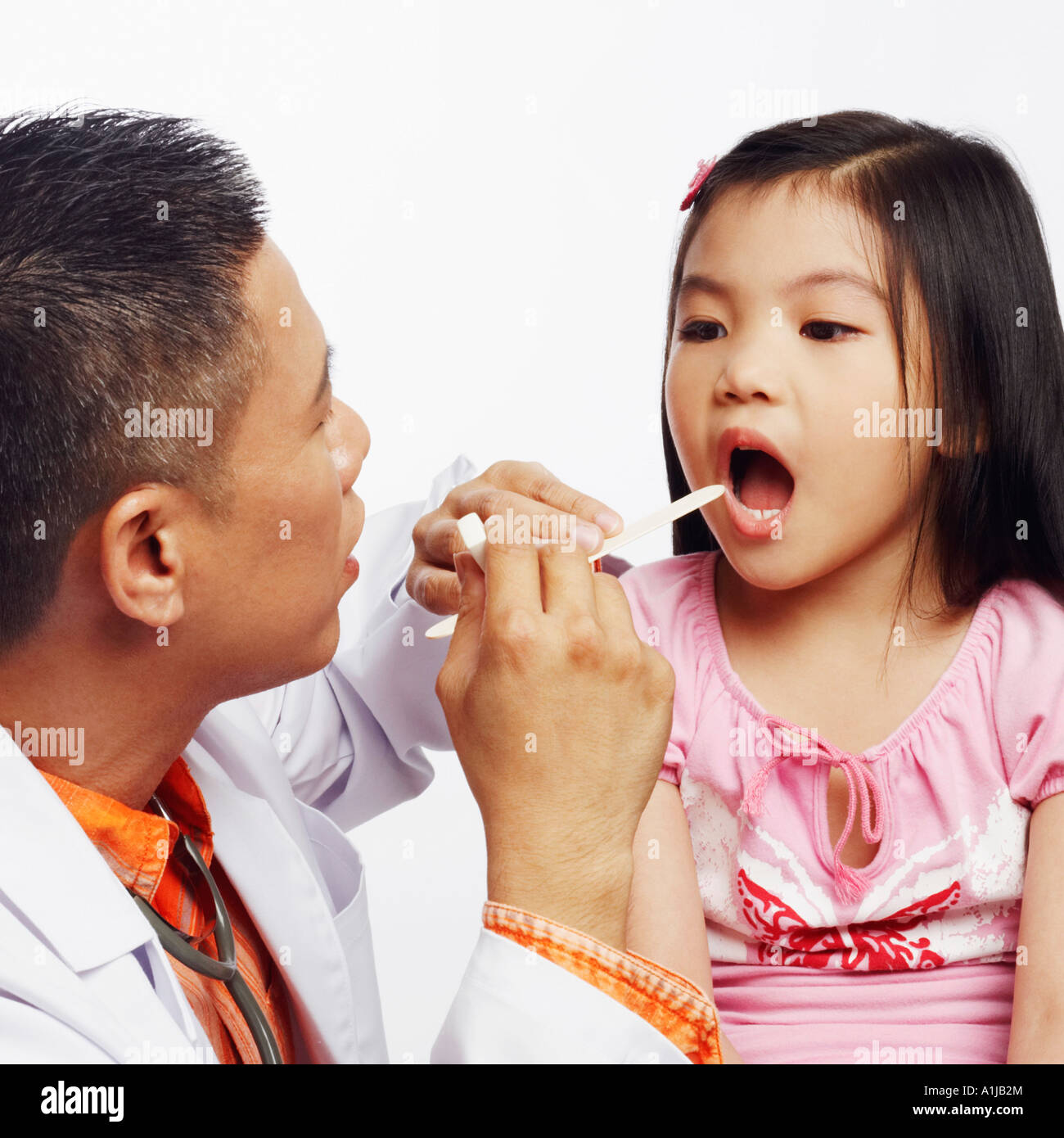 Closeup of a male doctor examining his patient with a tongue depressor