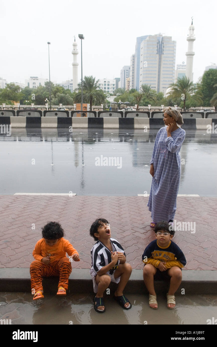 Abu Dhabi United Arab Emirates UAE November rain storm children playing in the rain watched over by their nanny member of staff 2006 2000s HOMER SYKES Stock Photo