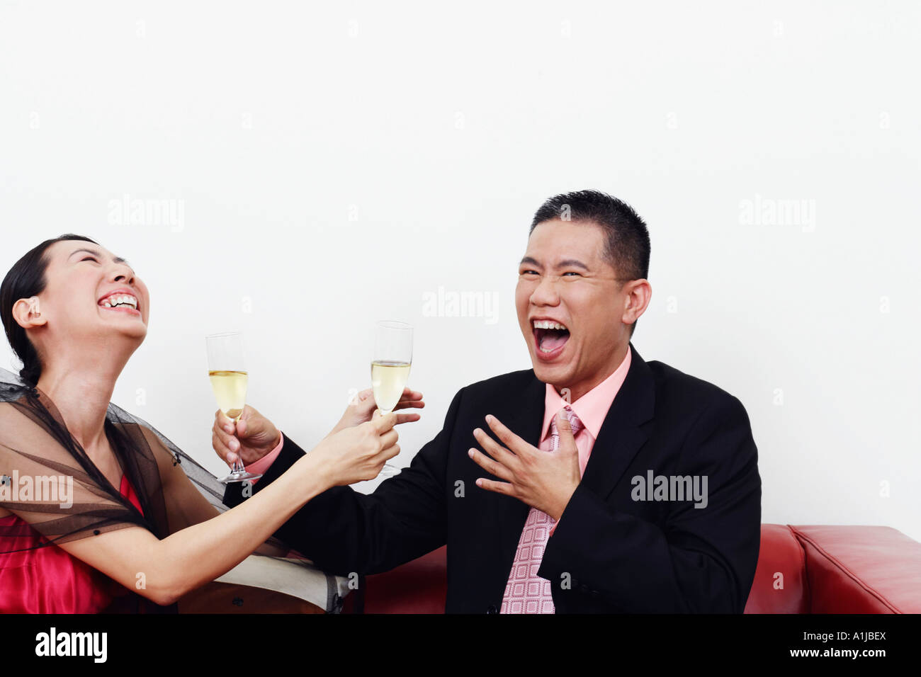 Close-up of a businessman and a mid adult woman holding glasses of champagne and laughing together Stock Photo