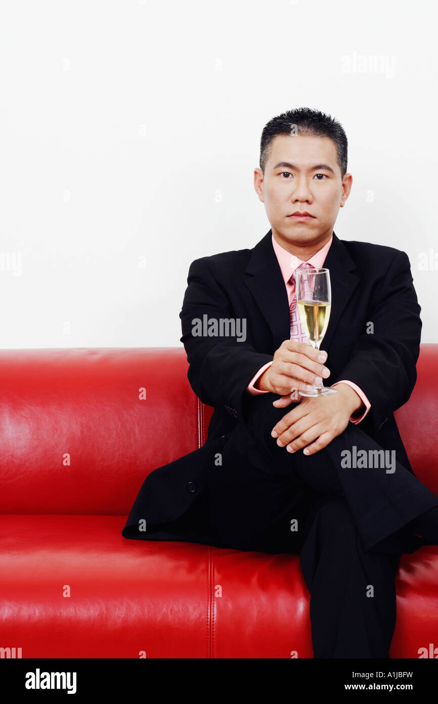 Portrait of a businessman sitting on a couch and holding a champagne flute Stock Photo
