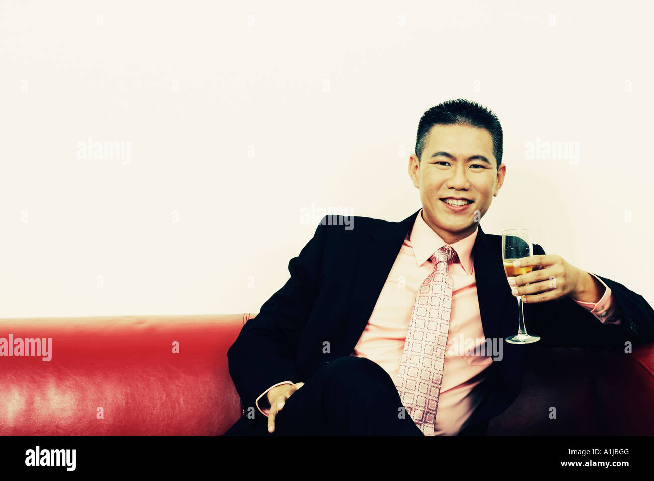 Portrait of a businessman holding a champagne flute and smiling Stock Photo