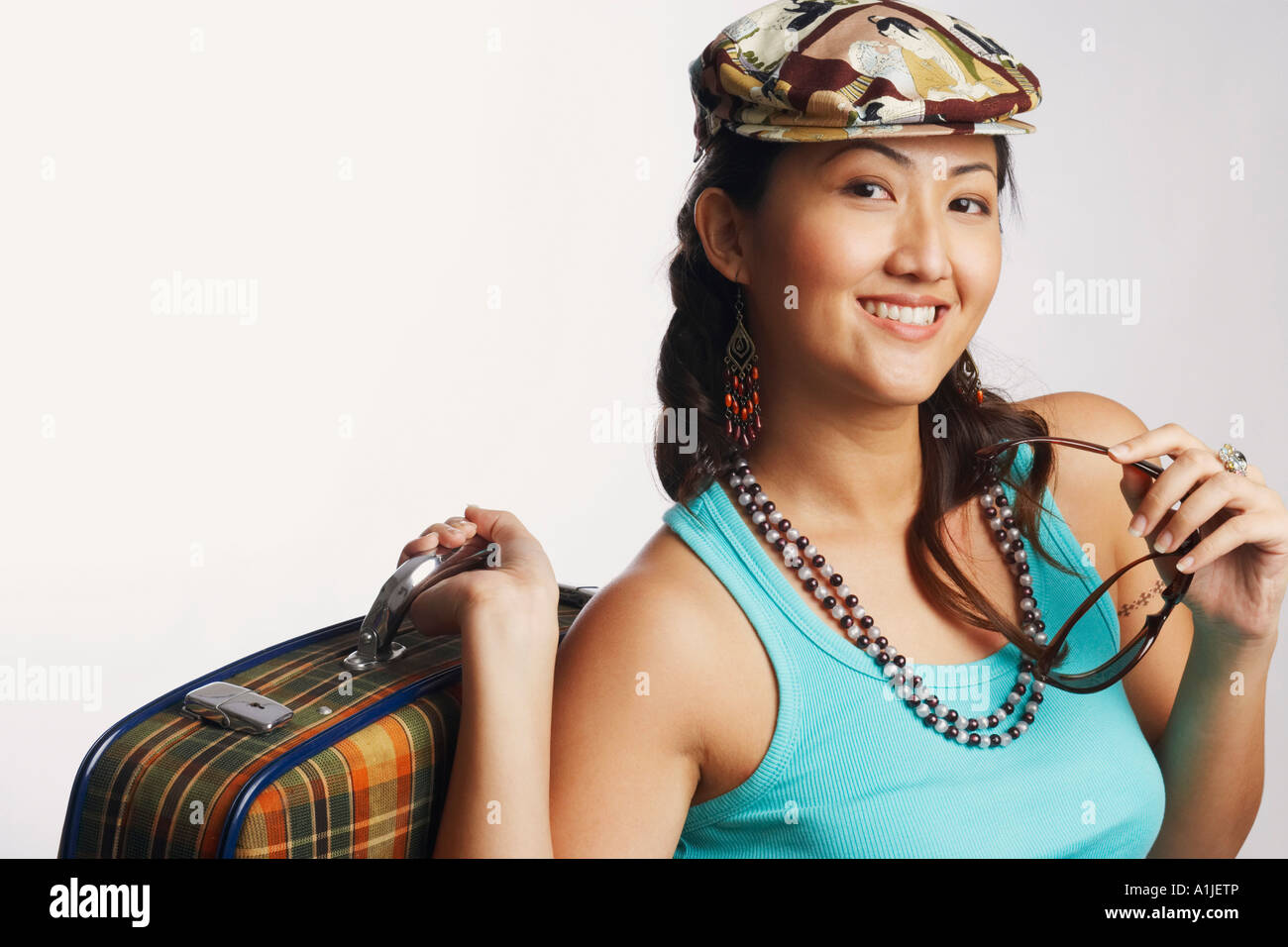 Portrait of a young woman holding sunglasses and a suitcase Stock Photo