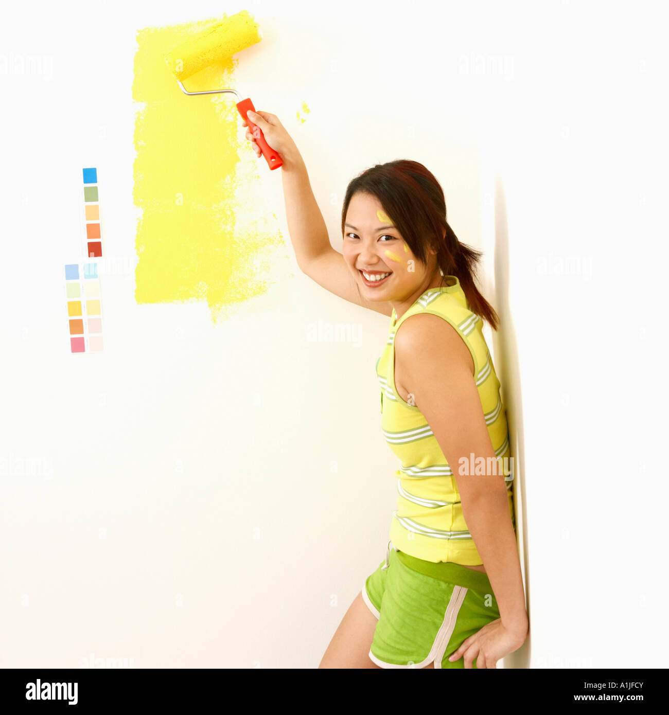 Portrait of a young woman painting a wall with a paint roller Stock ...