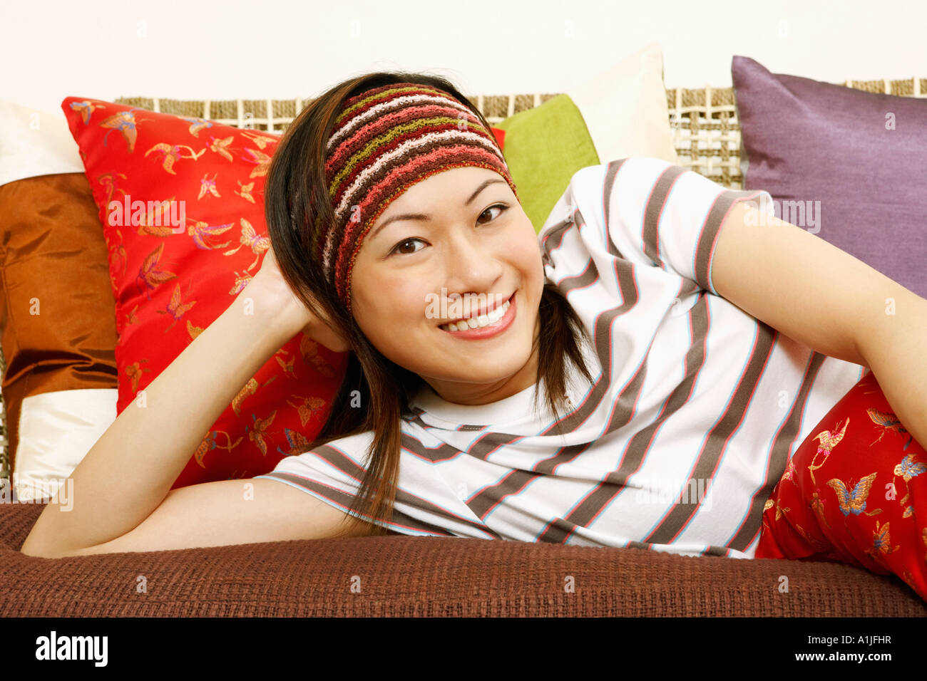 Portrait of a young woman lying on a couch and smiling Stock Photo - Alamy