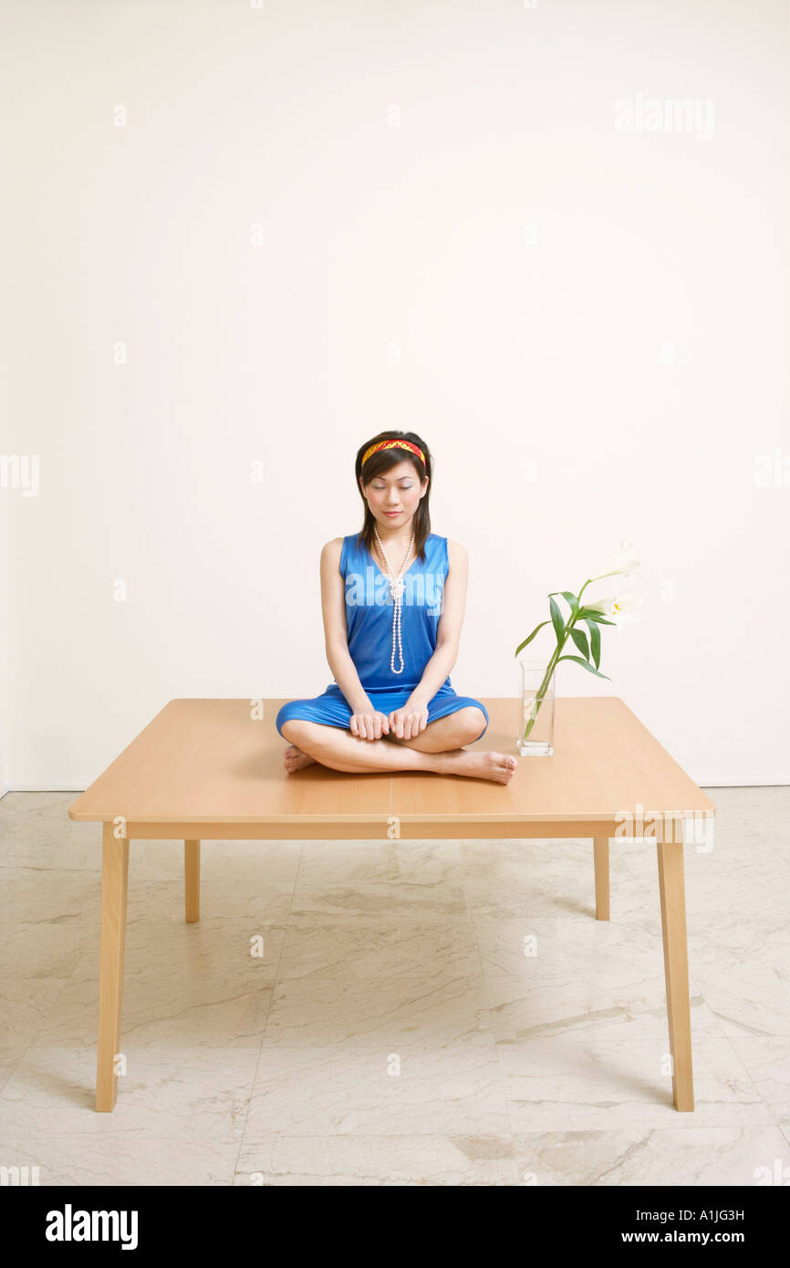 Young woman sitting on the table with her eyes closed Stock Photo