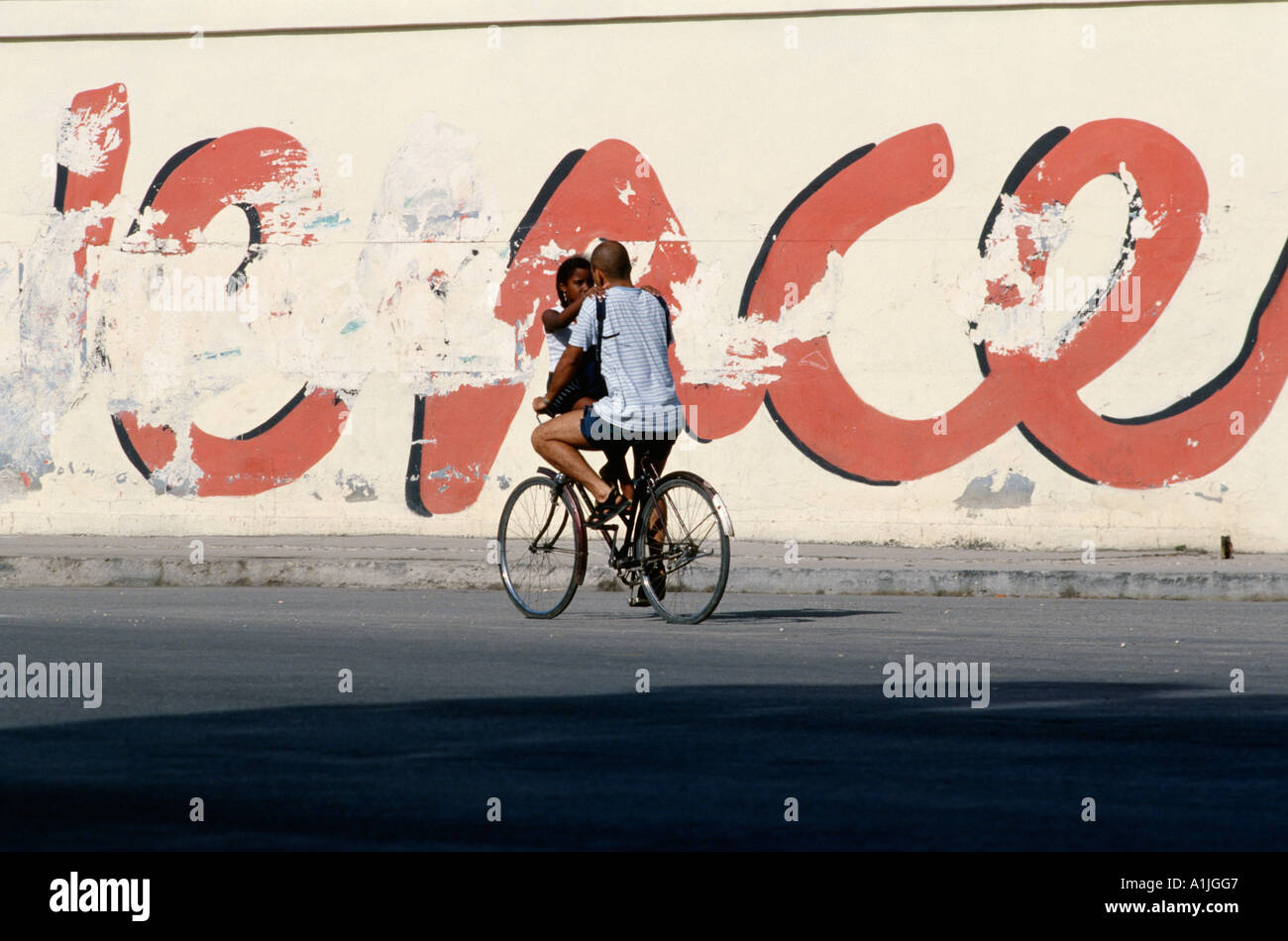 Havana Cuba Lovers on a bicycle with revolutionary slogans in background Stock Photo