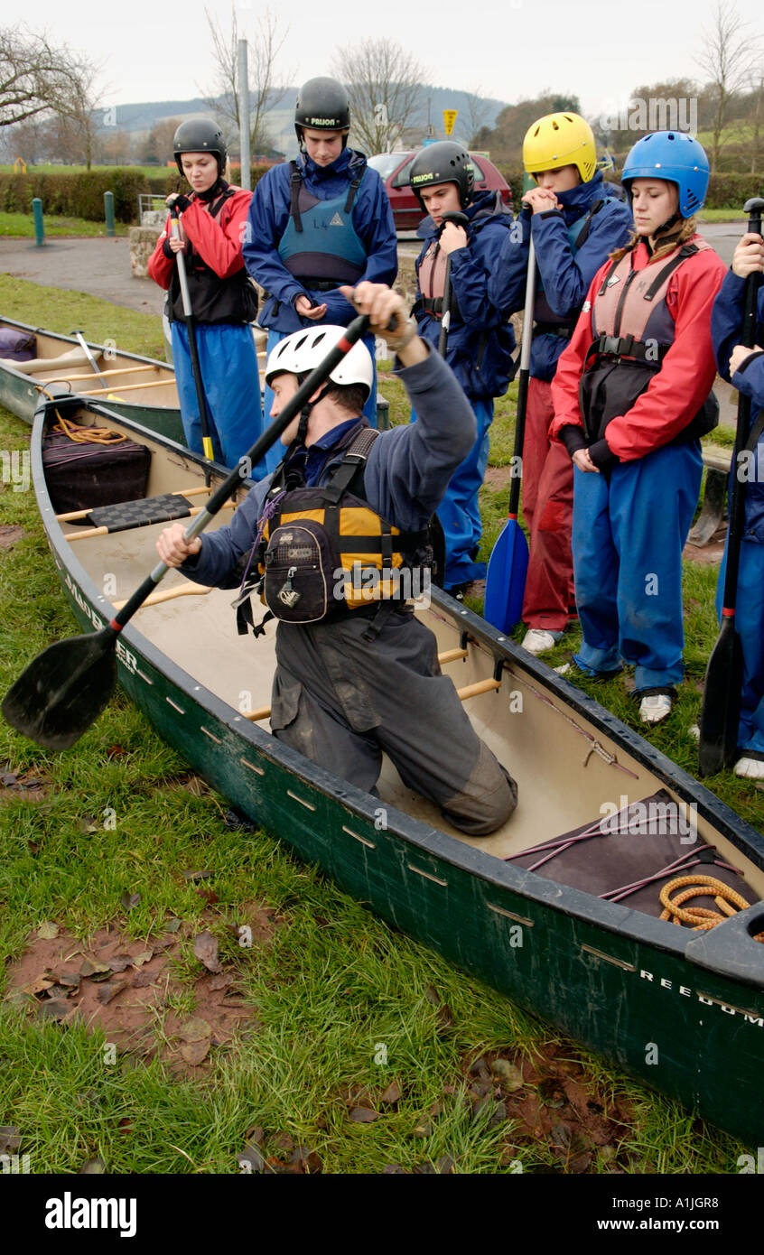 Instructor demonstrating open canoe technique to students on the banks