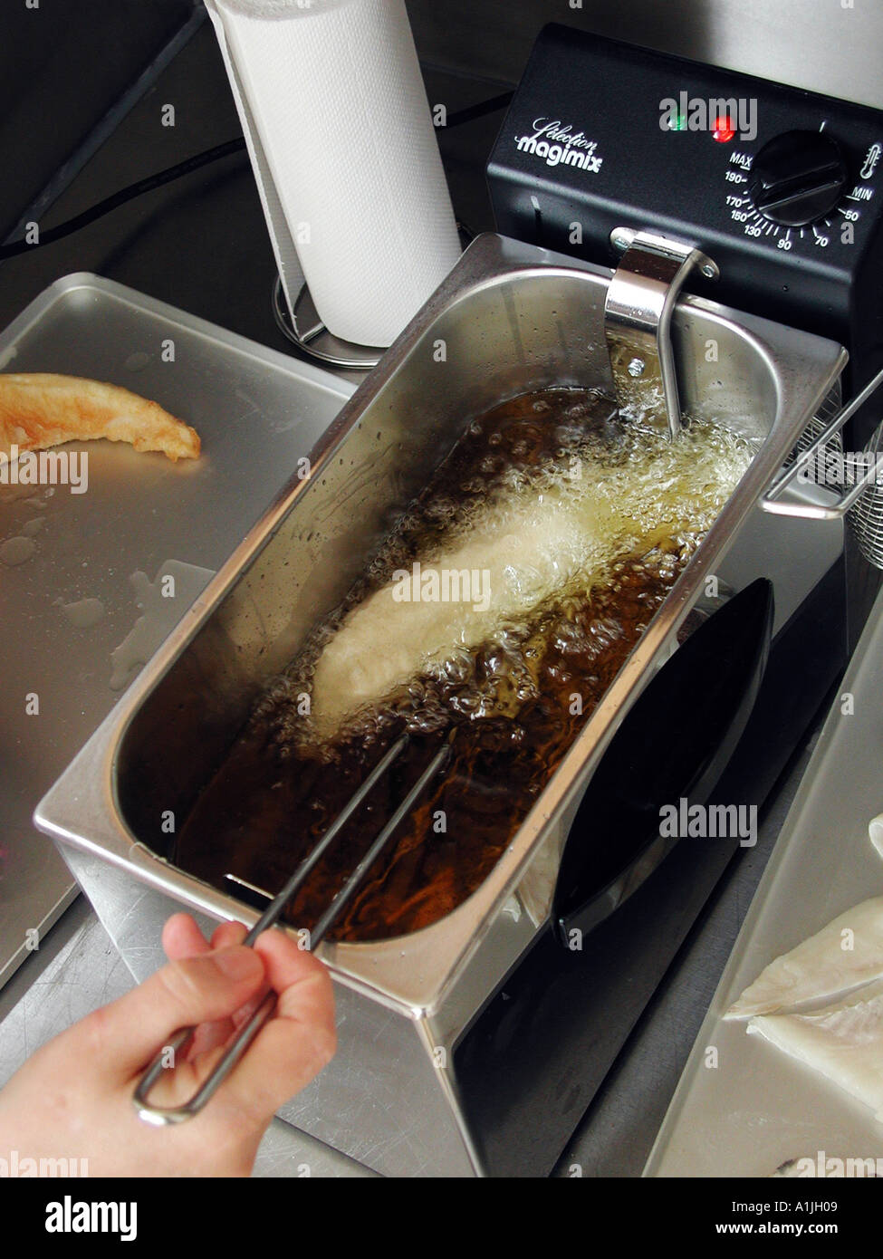 Frying fish in deep fat fryer Stock Photo Alamy