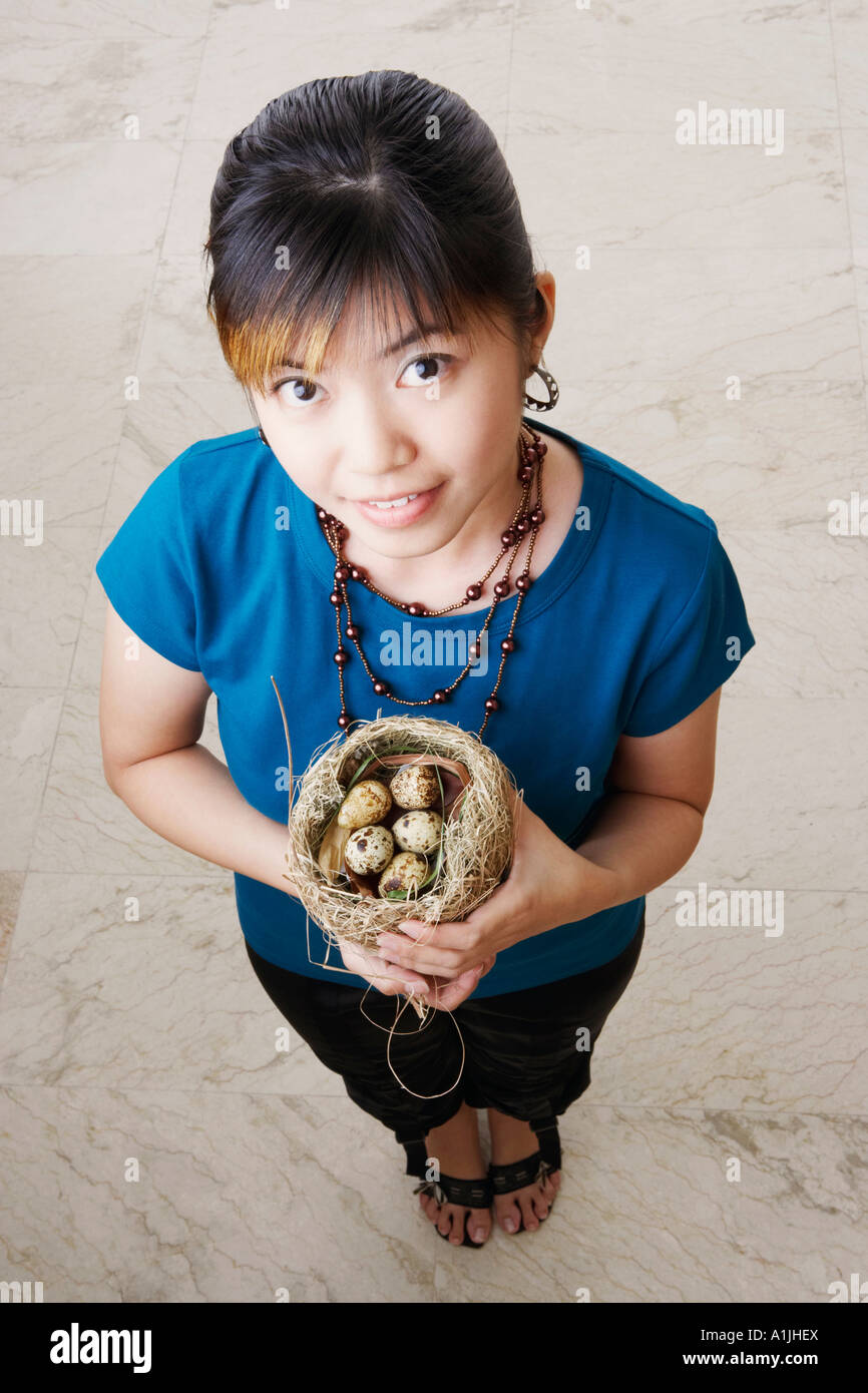 Portrait of a young woman holding a nest with eggs Stock Photo