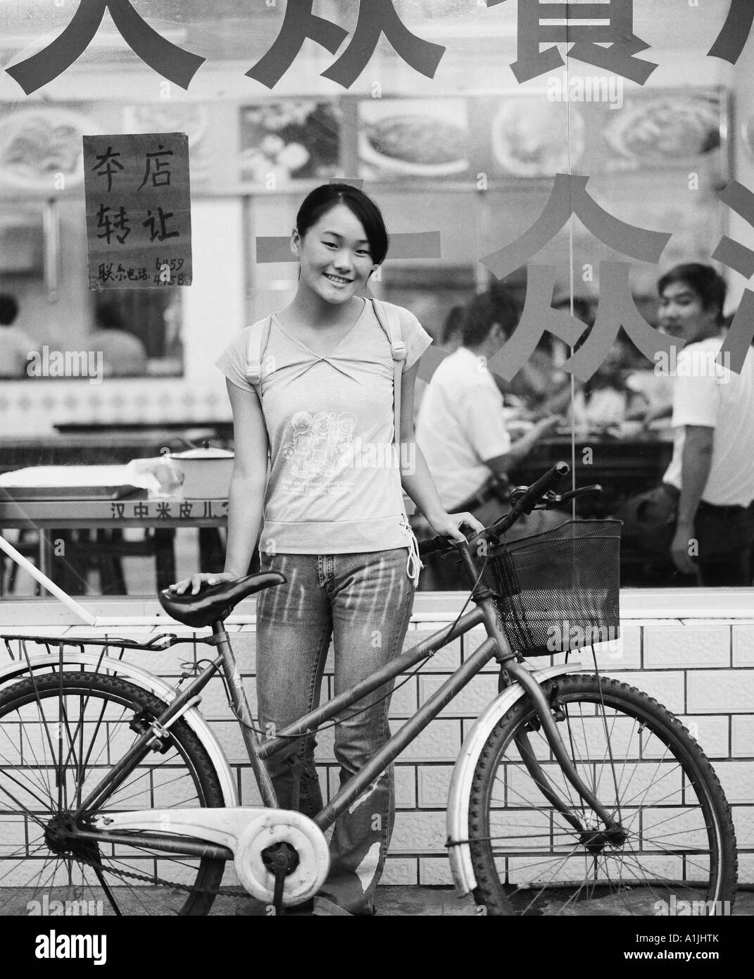 Portrait of a teenage girl standing with her bicycle in front of a restaurant Stock Photo