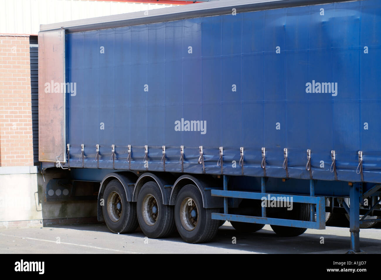 Articulated lorry unloading at unloading bay deliver transport transportation logistics road haulage lorry truck load unload fac Stock Photo